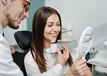 Smiling patient and dentist selecting shade of veneer