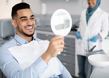 Patient smiling at reflection in handheld mirror