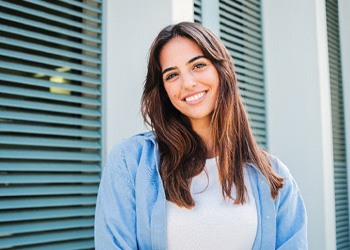 a smiling woman standing in front of a window