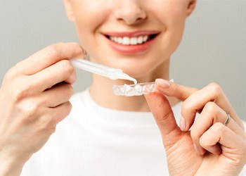 person putting whitening gel into a tray